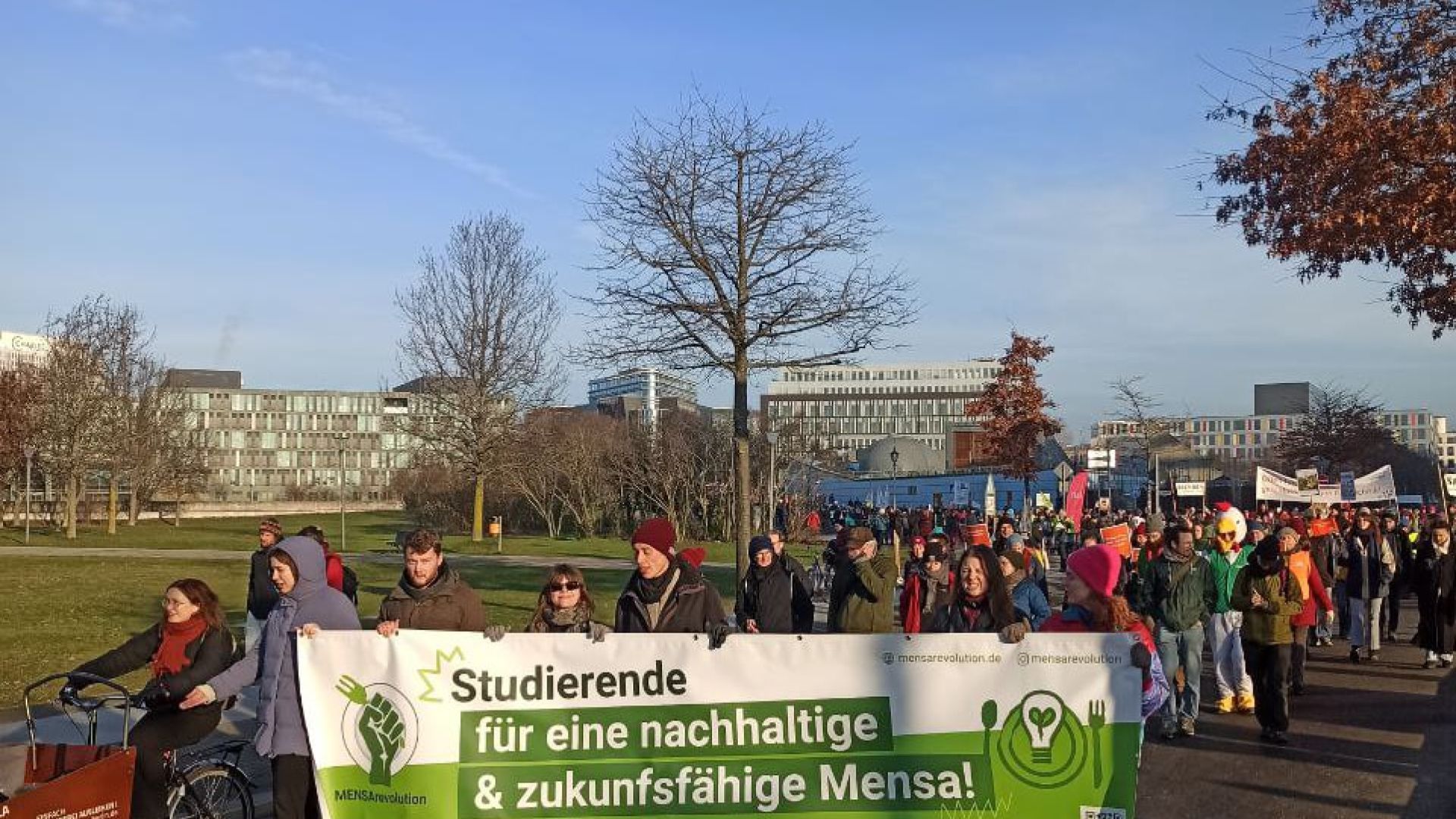 Ein Foto von Studierenden, die bei der "Wir haben es satt!"-Demonstration in Berlin mit dem Banner der Mensarevolution mitlaufen.